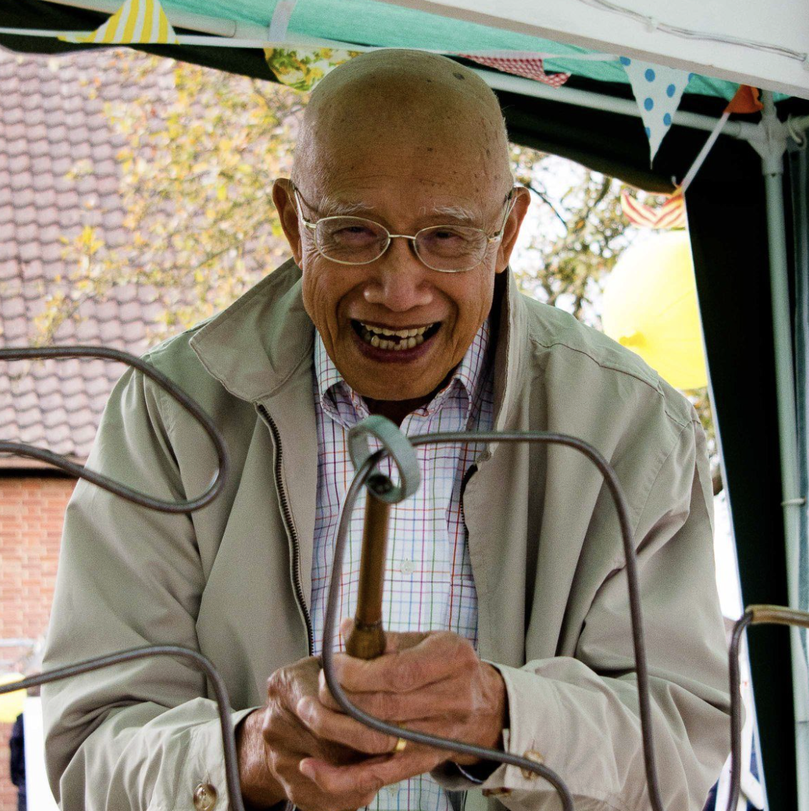 An older member of our church family at Collinwood Road United Reformed Church smiling while he plays a buzzer maze game at one of our community events.